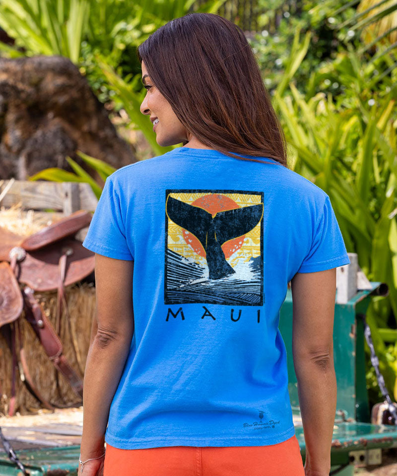 Woman wearing a blue t-shirt with a whale tail graphic and 'Maui' text, standing outdoors. View 2