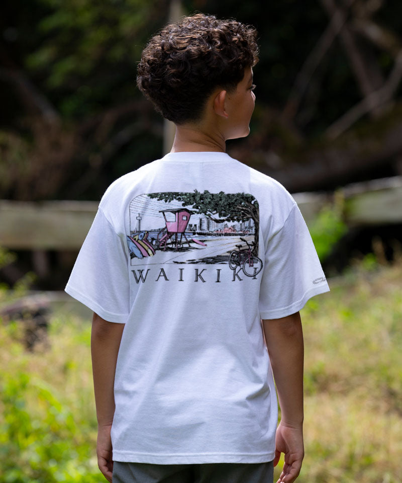 Person wearing a white t-shirt with a graphic design and 'Waikiki' text outdoors. View 2