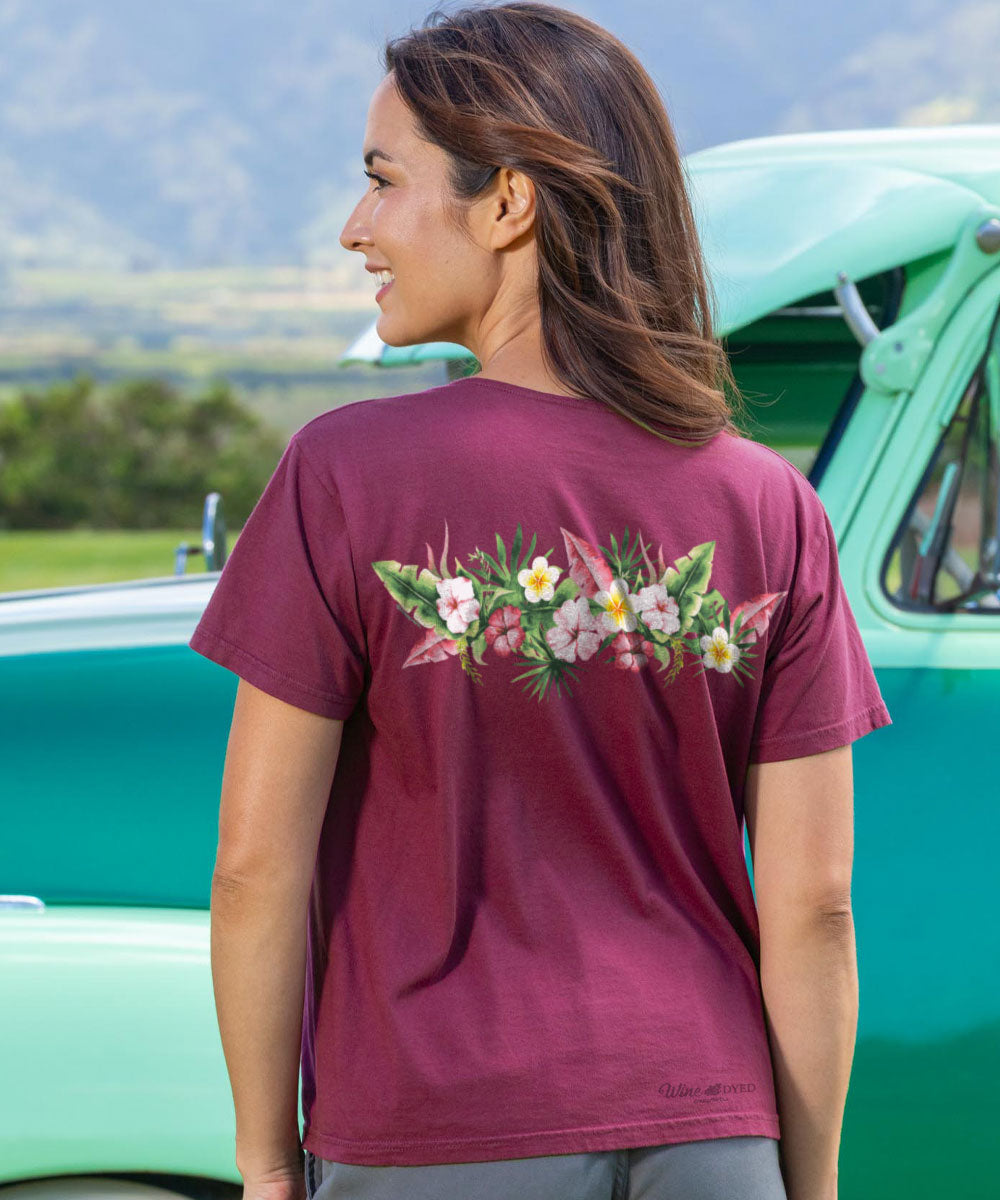 Woman wearing a purple t-shirt with floral design in front of a vintage green car. View 3