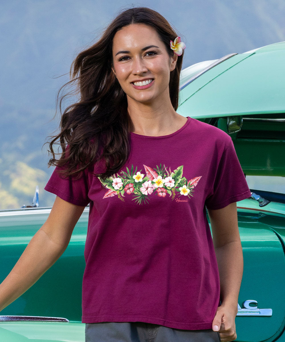 Woman wearing a purple t-shirt with floral design in front of a green vehicle. View 2
