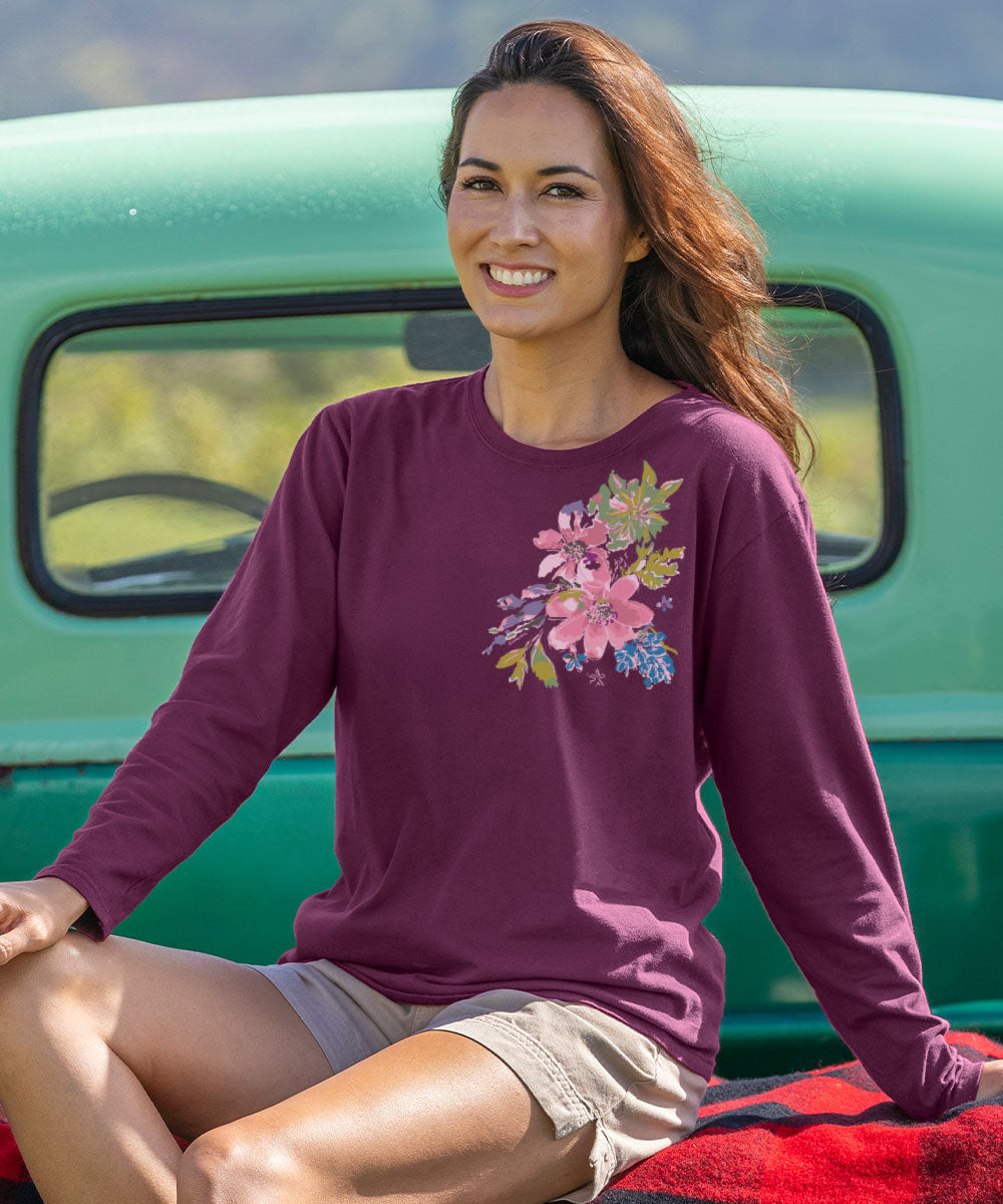 Woman wearing a purple long-sleeve shirt with floral design sitting in front of a green truck. View 2