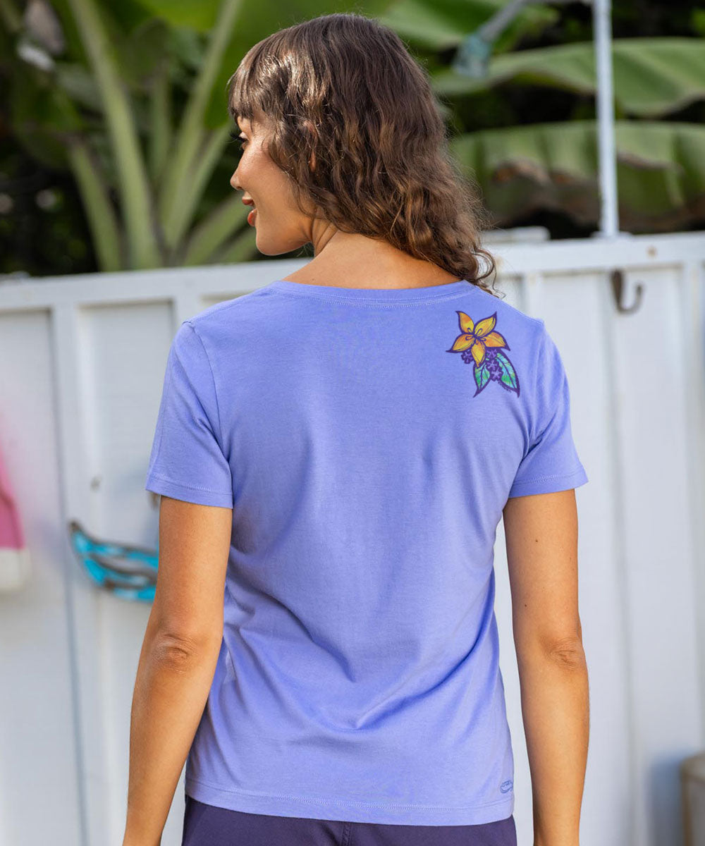 Person wearing a purple t-shirt with a colorful flower design on the back, standing outdoors. View 3