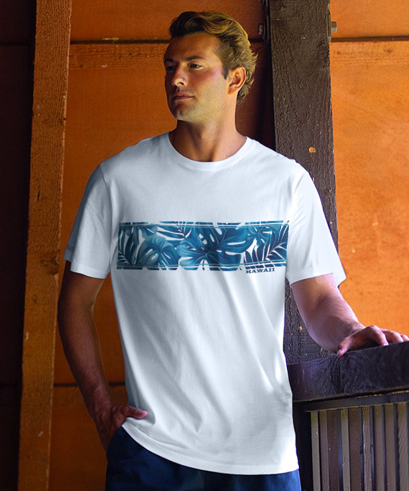 Man wearing a white t-shirt with a blue graphic design, standing against an orange wall. View 2