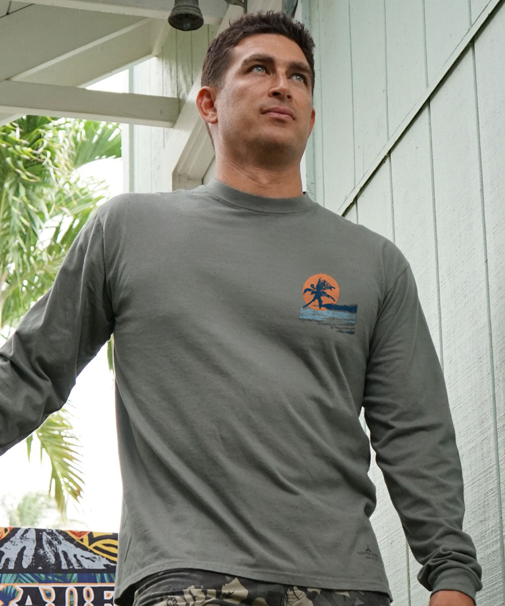 Man wearing a gray long-sleeve shirt with a logo, standing outdoors. View 3