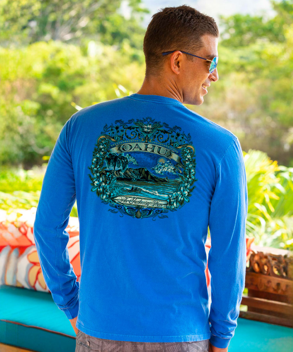 Man wearing a blue long-sleeve shirt with a tropical design on the back, standing outdoors. View 2