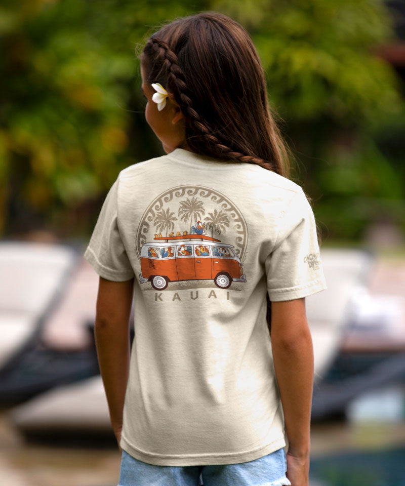 Person wearing a t-shirt with a graphic design of a van and palm trees, standing outdoors. View 2
