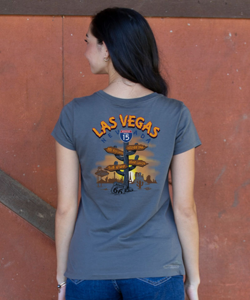 Person wearing a blue t-shirt with 'Las Vegas' text and graphic on the back, standing against a red wall. View 2