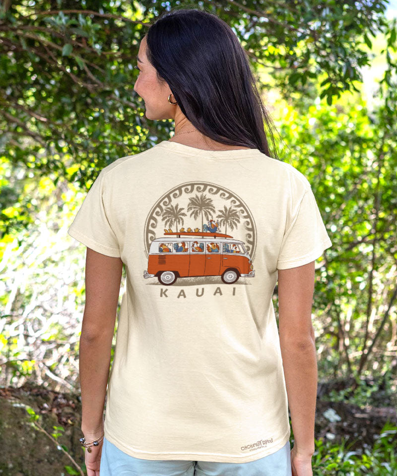 Person wearing a t-shirt with a van and palm tree design, standing in a forest. View 2