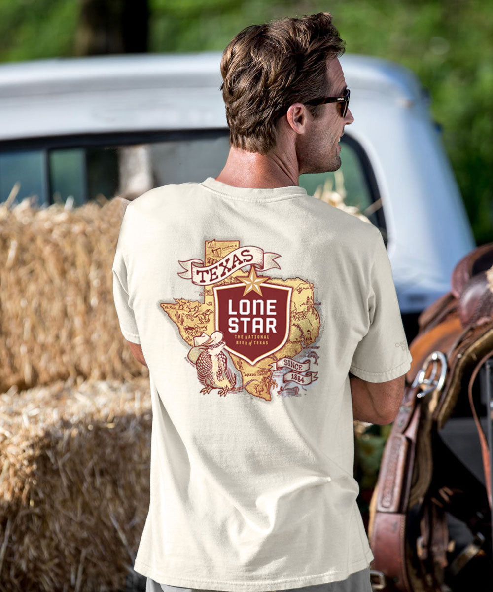 Man wearing a creamy white t-shirt with 'Texas Lone Star' design, standing outdoors near hay bales.