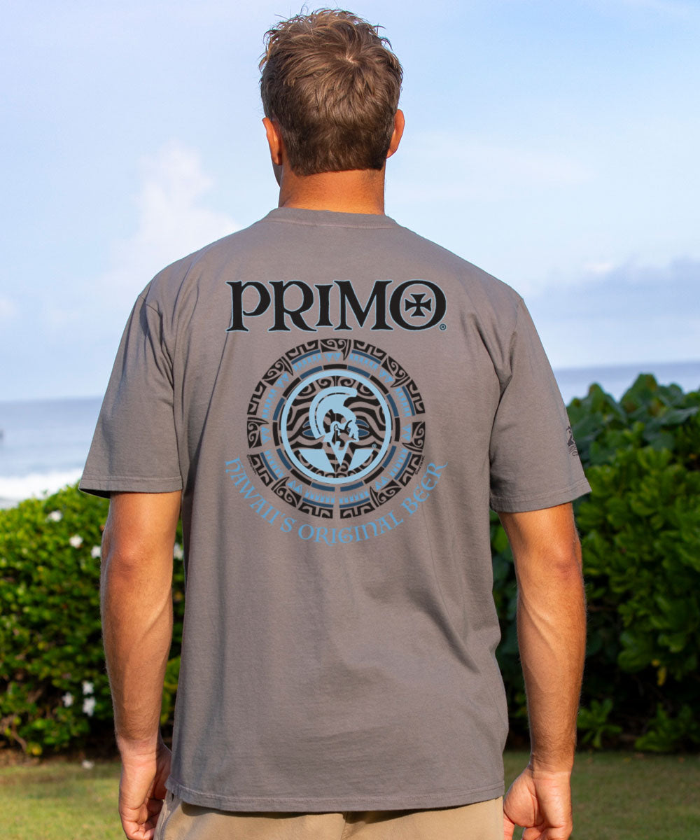 Man wearing a gray 'Primo' t-shirt with a logo on the back, standing outdoors. View 2