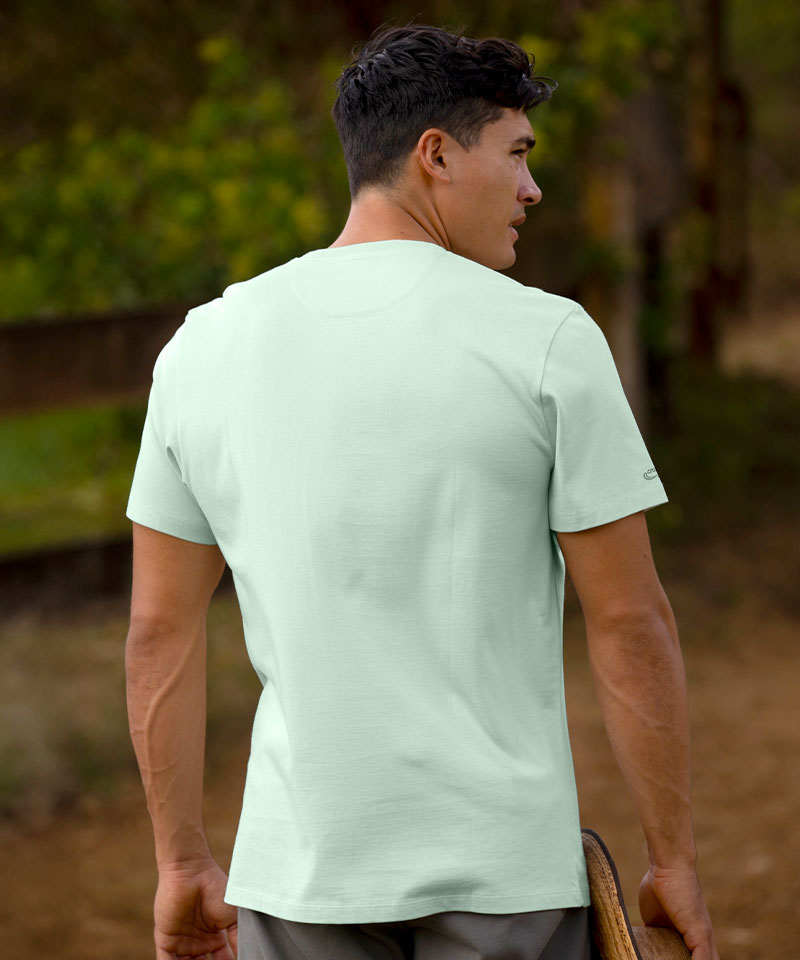 Man wearing a light green t-shirt standing outdoors with trees in the background View 3