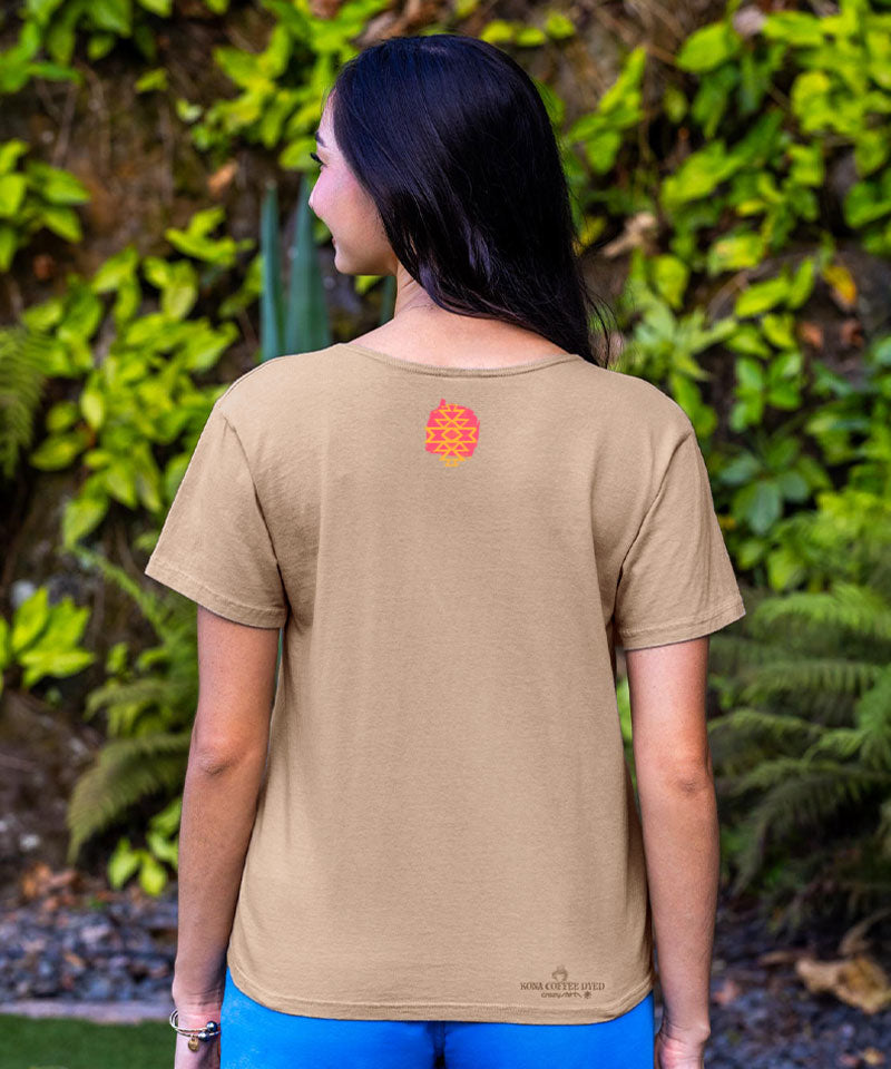 Person wearing a beige t-shirt with a logo on the back, standing in front of green foliage. View 3