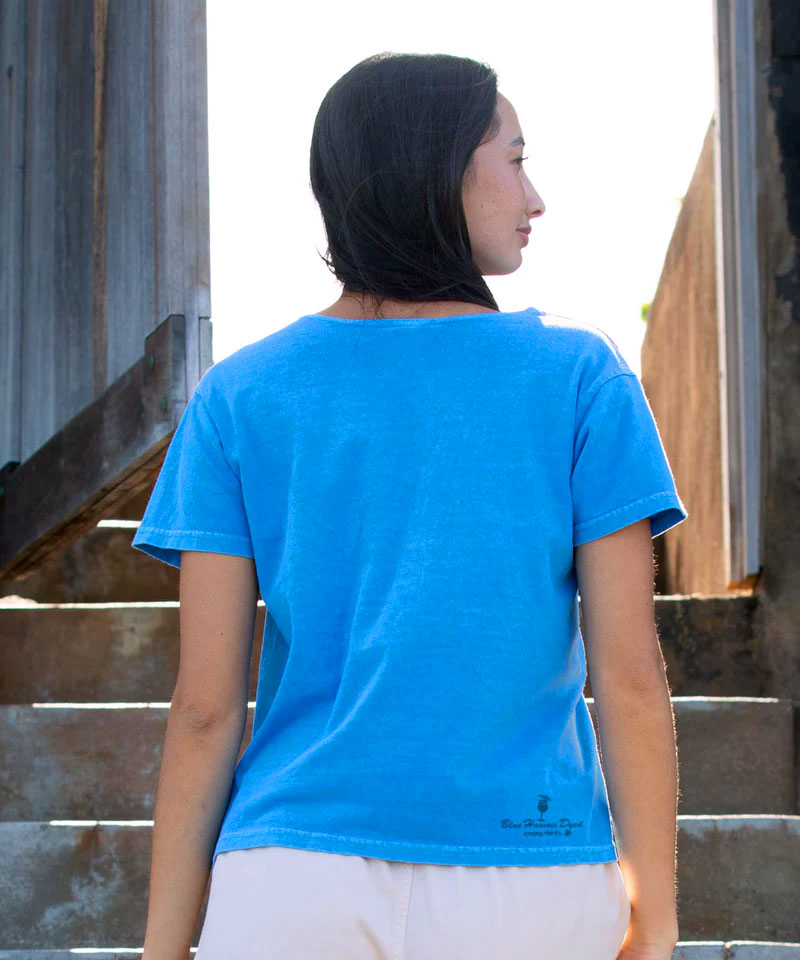 Person wearing a blue t-shirt standing on steps with a neutral background View 3