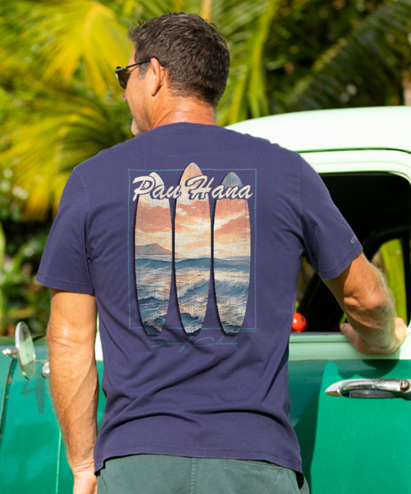 Man wearing an indigo t-shirt with a logo on the back standing next to a car. View 2