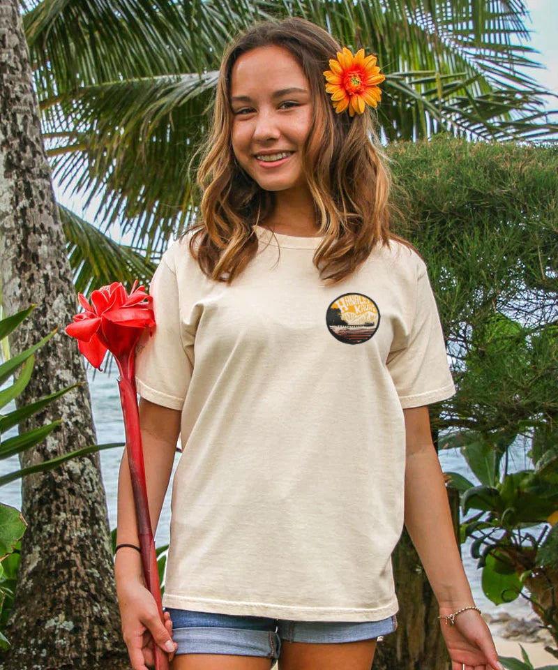 Woman wearing a t-shirt with a circular design, standing outdoors with palm trees in the background View 3