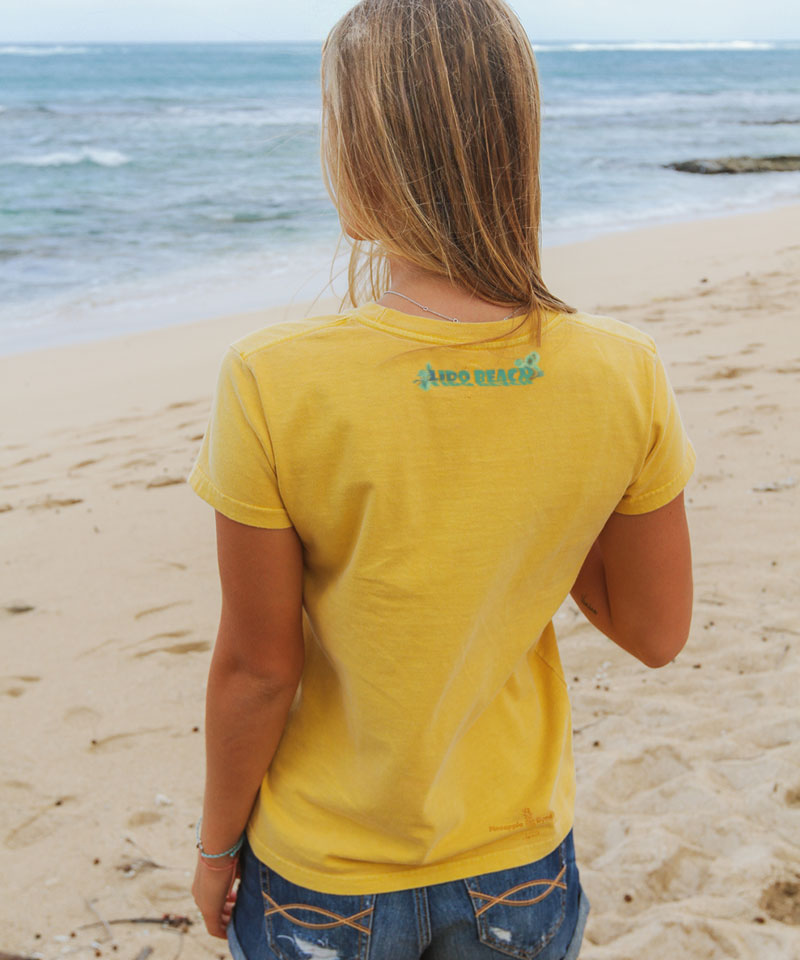 Person wearing a yellow t-shirt with a brand logo on the beach View 3