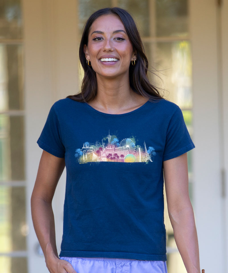 Woman wearing a blue t-shirt with a colorful graphic design, standing outdoors. View 2