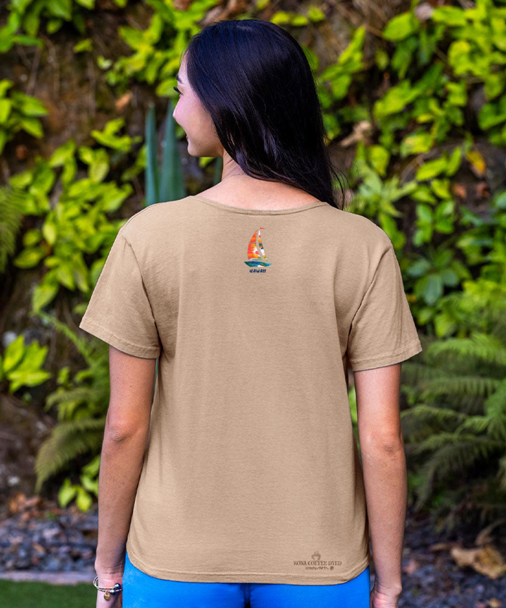 Person wearing a beige t-shirt with a logo on the back, standing in front of green foliage. View 3