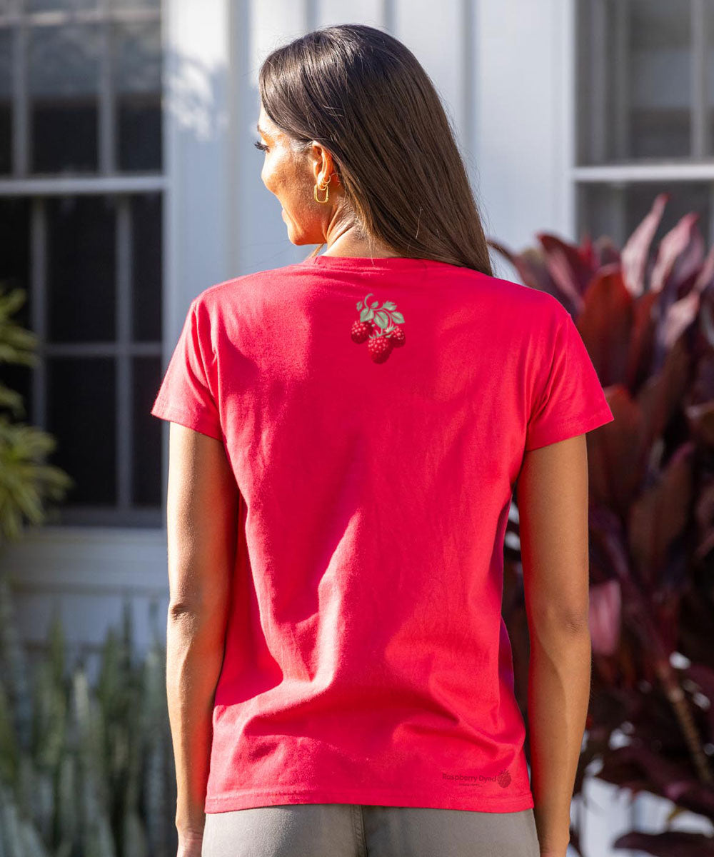Person wearing a raspberry dyed t-shirt with a floral design on the back, standing outdoors. View 3