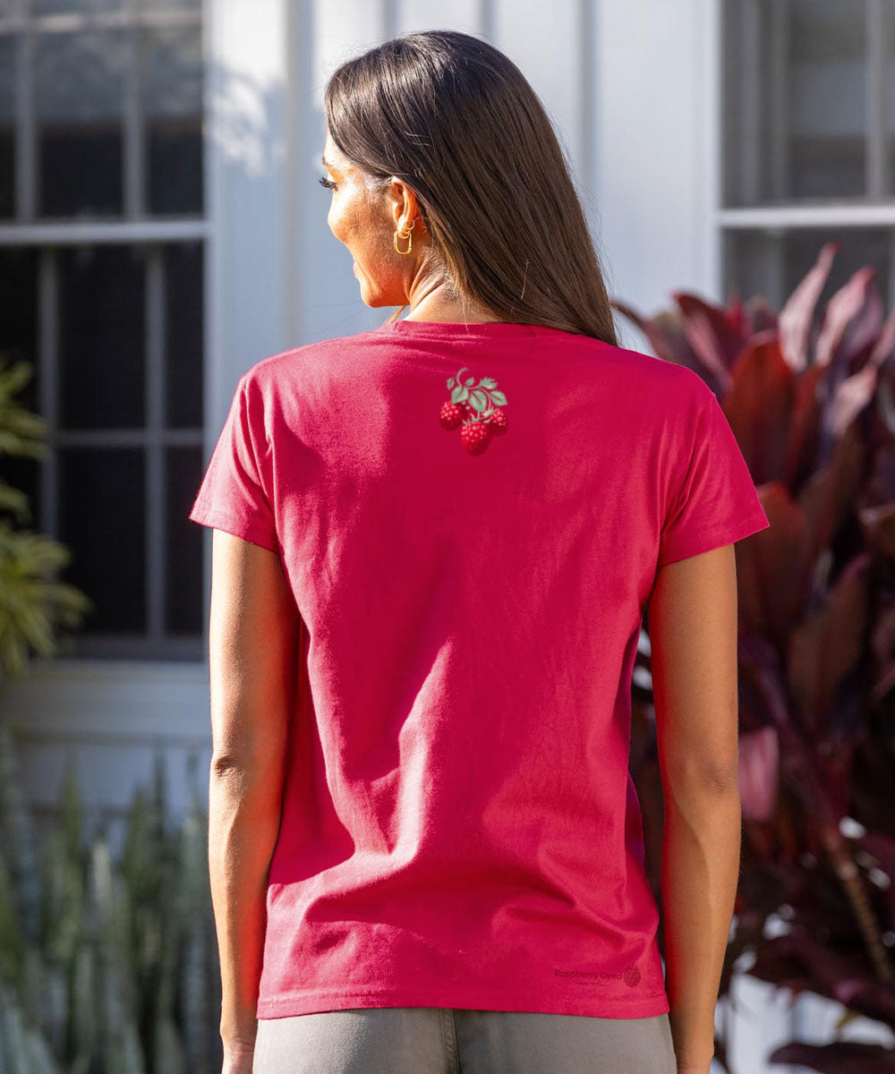 Person wearing a raspberry dyed t-shirt with a floral design on the back, standing outdoors. View 3