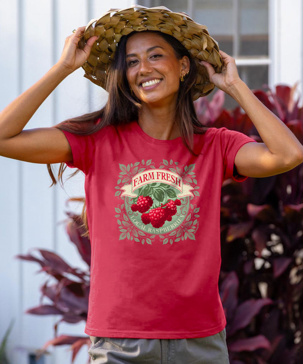 Person wearing a raspberry dyed 'Farm Fresh' t-shirt with a straw hat, standing outdoors. View 2
