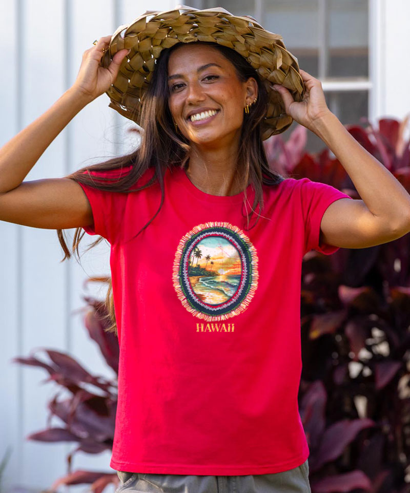 Woman wearing a raspberry dyed 'Hawaii' t-shirt with a scenic design, standing outdoors. View 2
