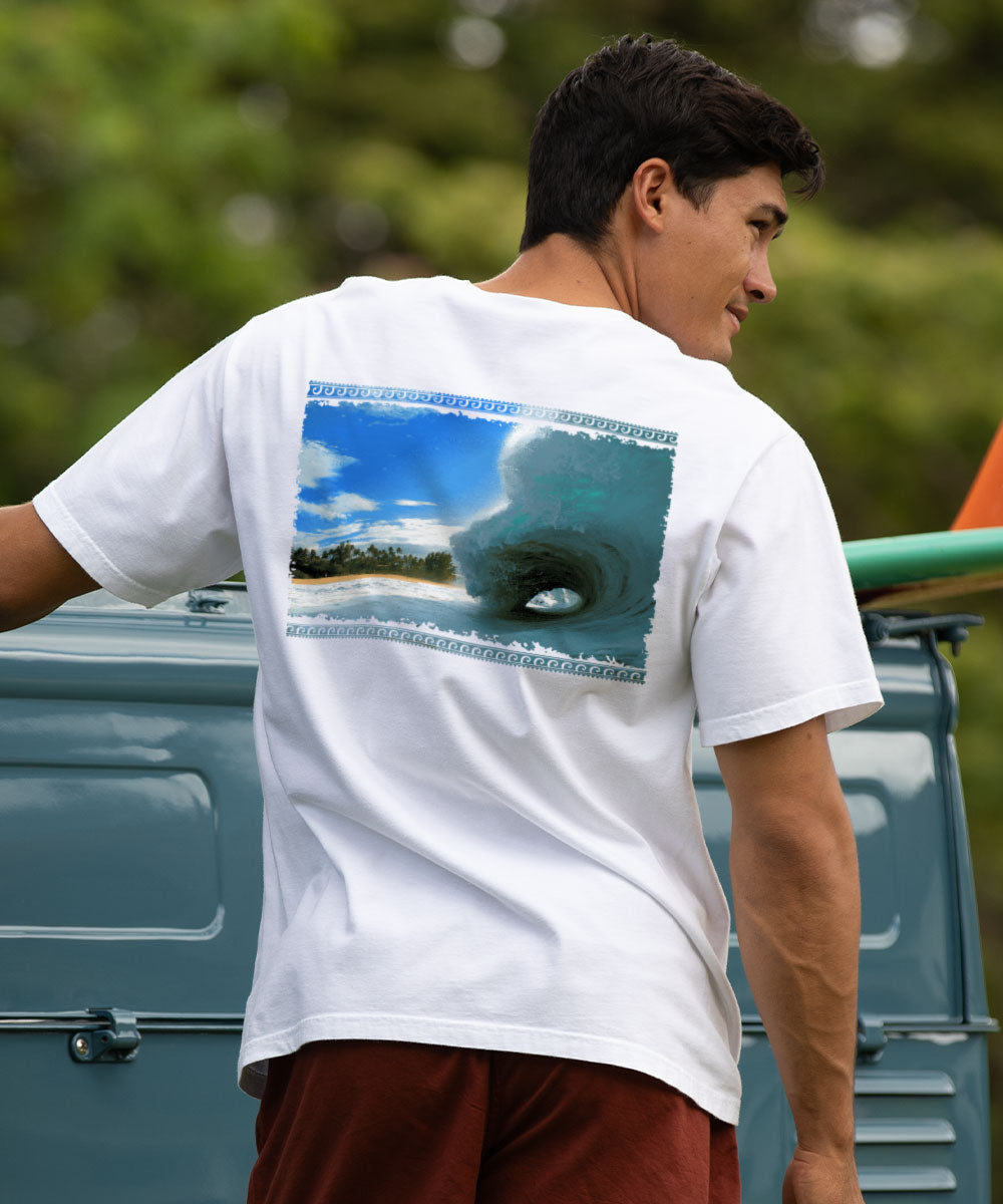Man wearing a white t-shirt with a graphic of a wave on the back, standing next to a truck. View 2