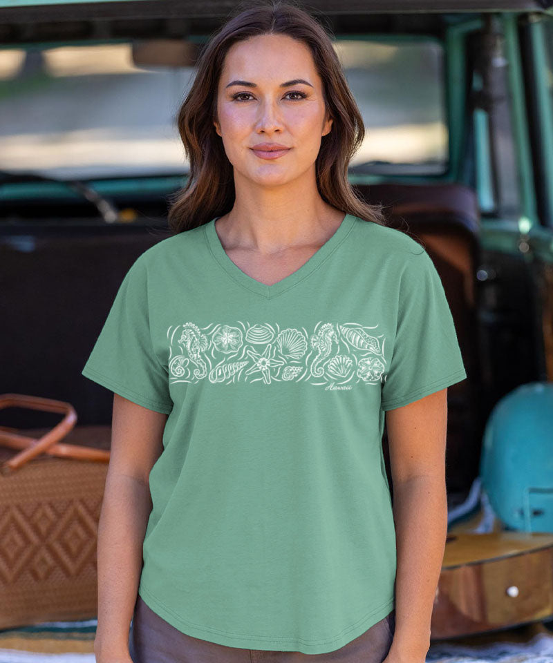 Woman wearing a green t-shirt with a white graphic design, standing in front of a vehicle. View 2