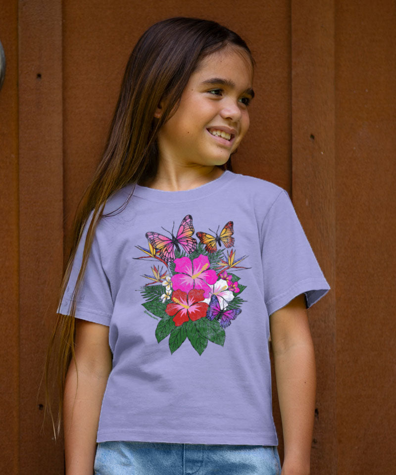 Young girl wearing a purple t-shirt with floral and butterfly design against a brown background View 2