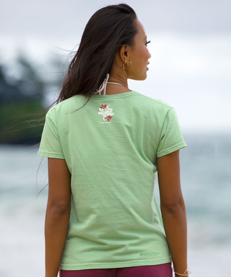 Woman wearing a light green t-shirt with a floral design on the back, standing outdoors. View 3