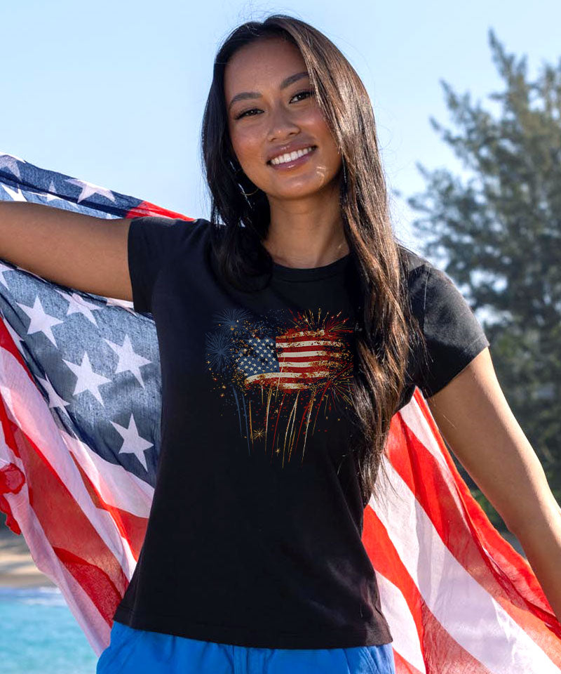 Woman holding an American flag wearing a black t-shirt with a graphic design. View 2