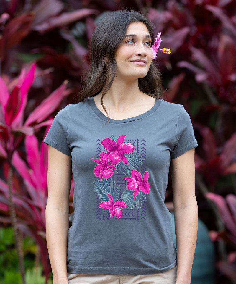 Woman wearing a gray t-shirt with pink floral design in front of pink and purple foliage. View 2