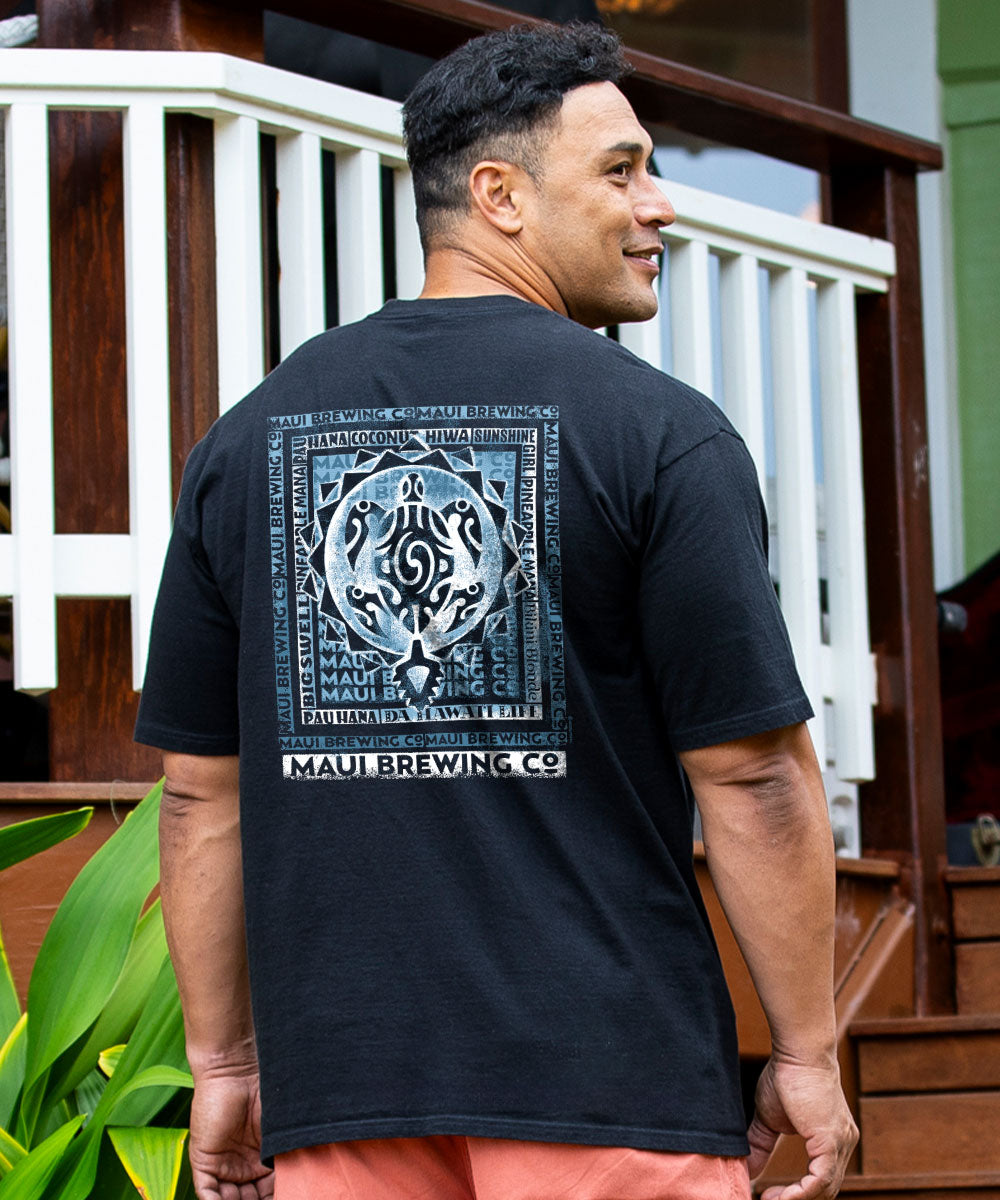 A man wearing a black short-sleeve t-shirt with a large blue and white Polynesian tribal graphic on the back, featuring the text 'MAUI BREWING CO'. View 2