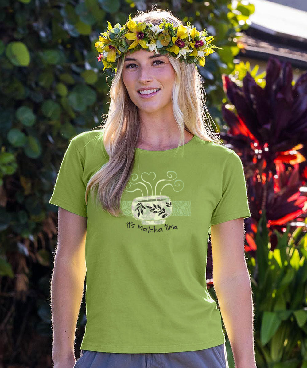 Woman wearing a green t-shirt with a design and floral headband, standing outdoors. View 2