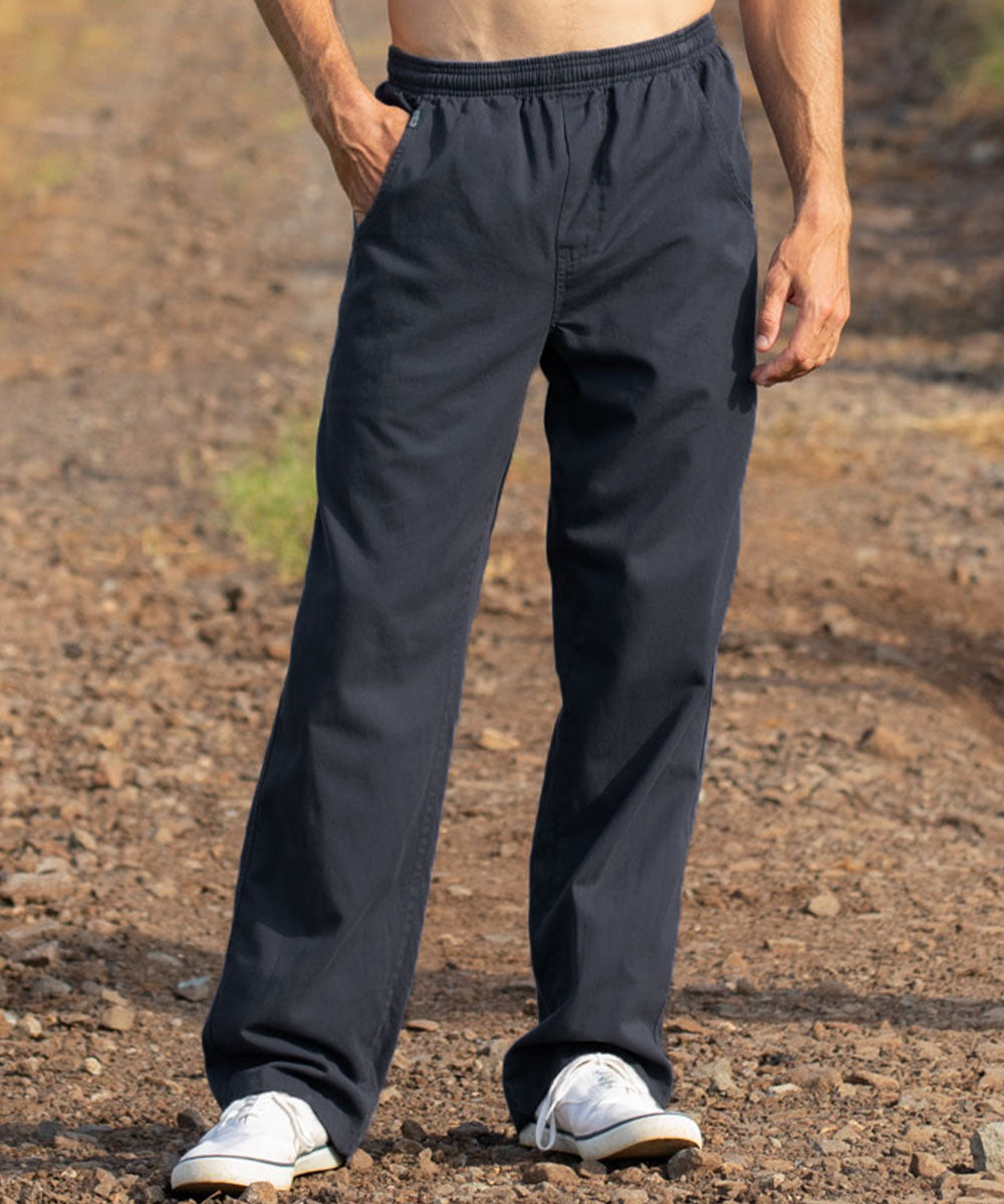 A person wearing dark navy drawstring pants and white sneakers, standing outdoors on a gravel path. View 2
