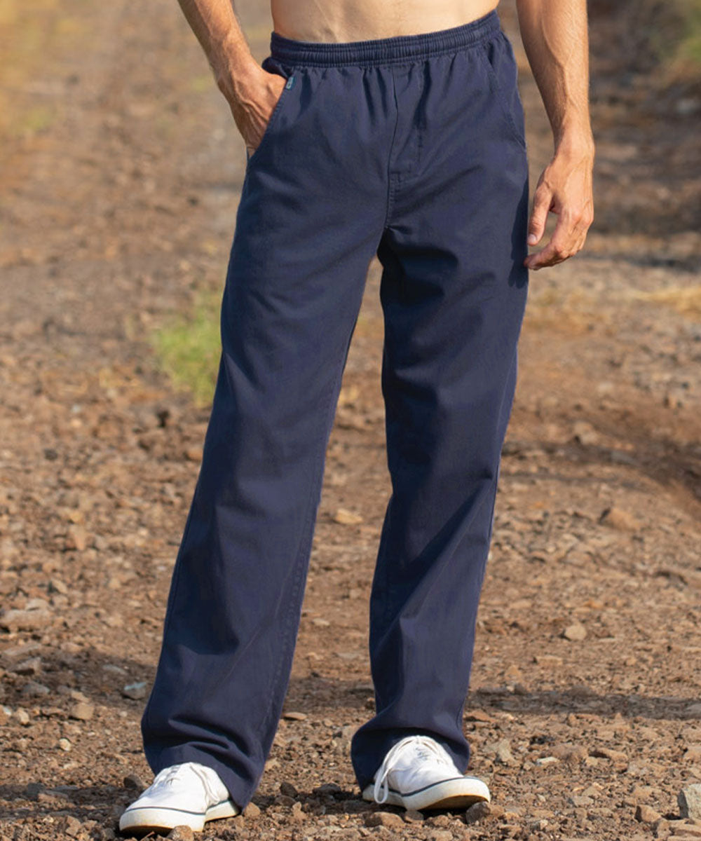 A person wearing dark navy drawstring pants and white sneakers, standing outdoors on a gravel path. View 2