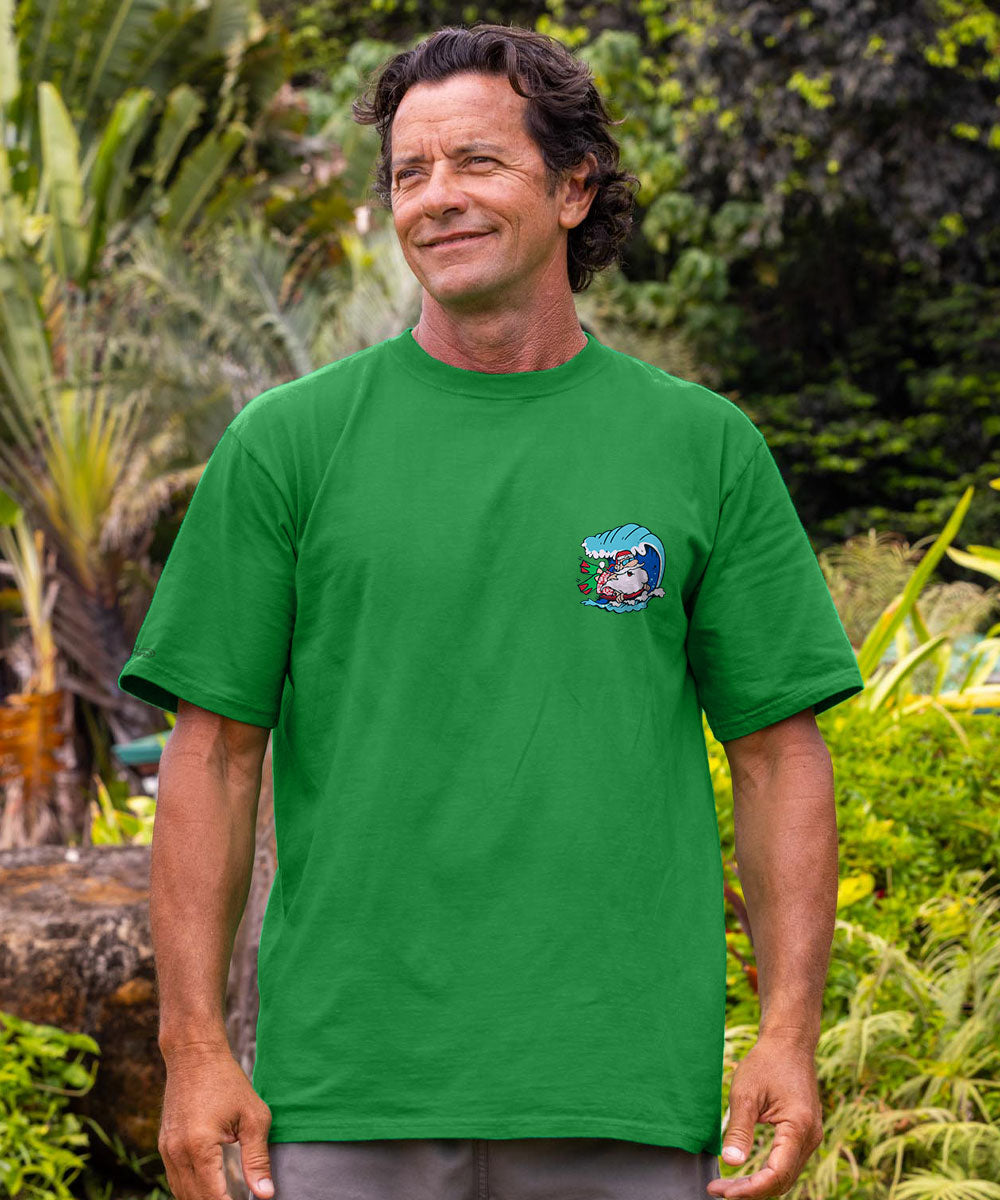 A man wearing a bright green short-sleeve t-shirt with a small cartoon graphic on the left chest, standing outdoors in a lush green garden. View 3
