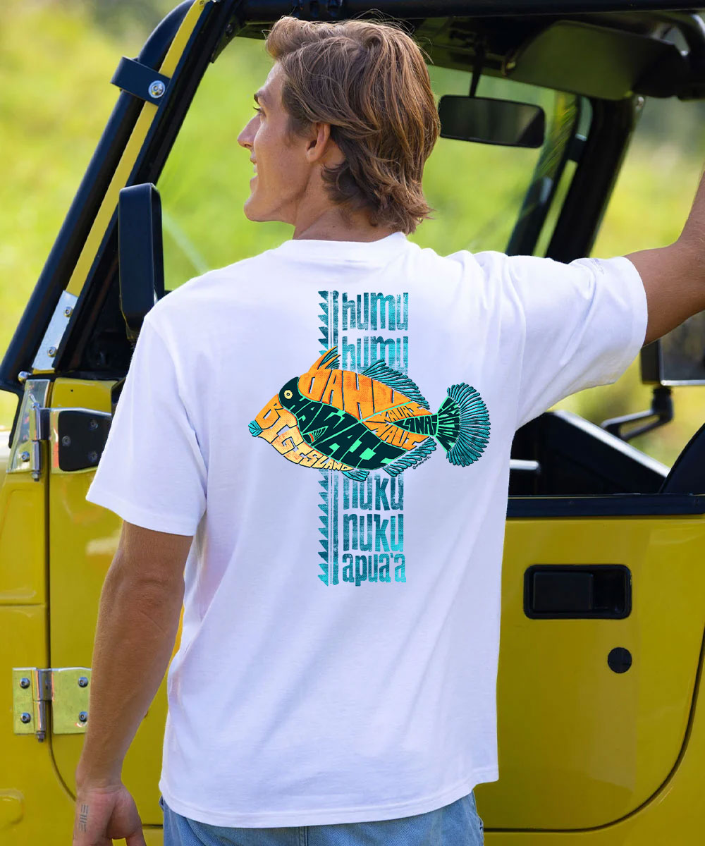A man wearing a white t-shirt with a colorful back graphic, standing next to a yellow vehicle outdoors. View 2