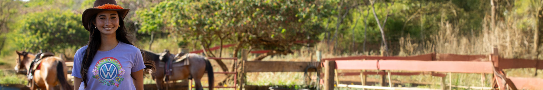 Woman in a hat and t-shirt standing with horses in a field