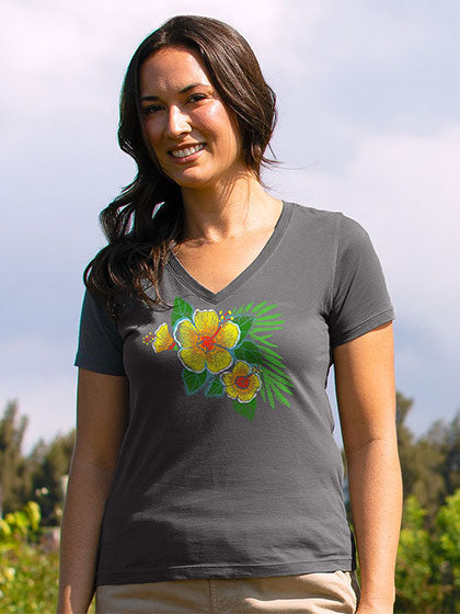 A woman wearing a dark gray v-neck t-shirt with a colorful graphic of yellow hibiscus flowers and green leaves, photographed outdoors against a cloudy sky.