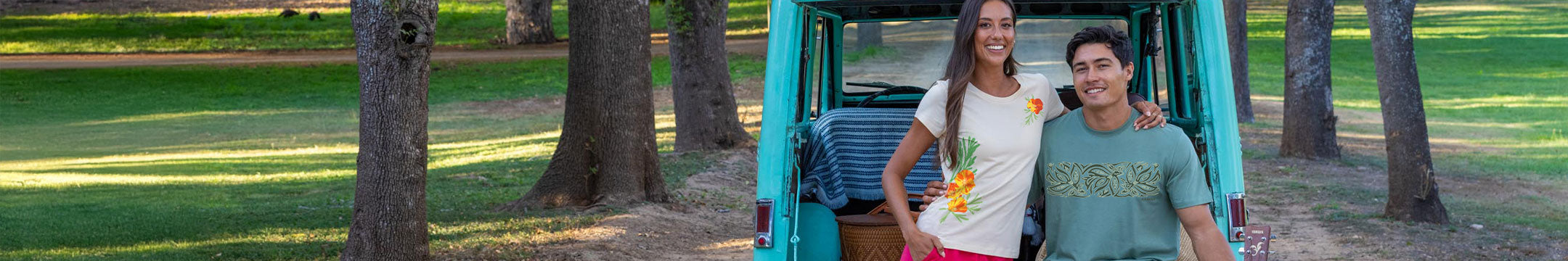 Two people standing next to a teal vehicle in a park with trees and grass.
