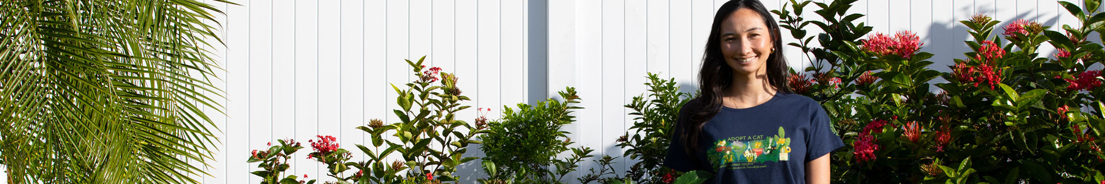 Woman standing in front of a white wall with greenery and flowers