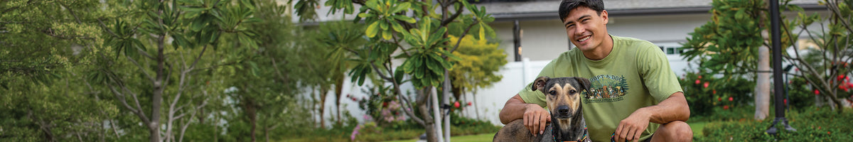 Man sitting on grass with a dog in a garden setting