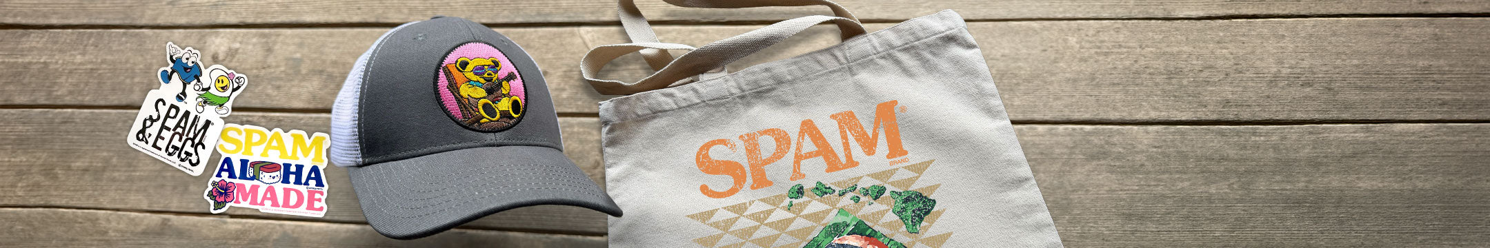 A collection of various items including stickers, a hat, and a tote bag on a wooden surface