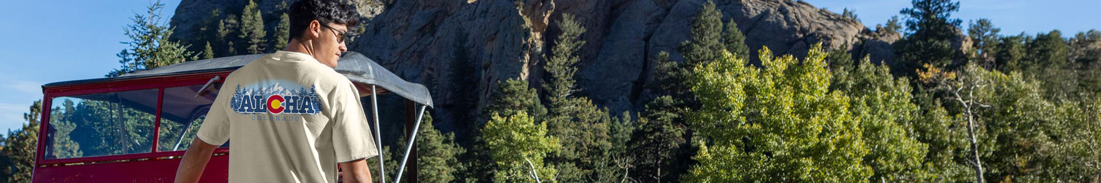 Person standing on a boat with mountains and trees in the background