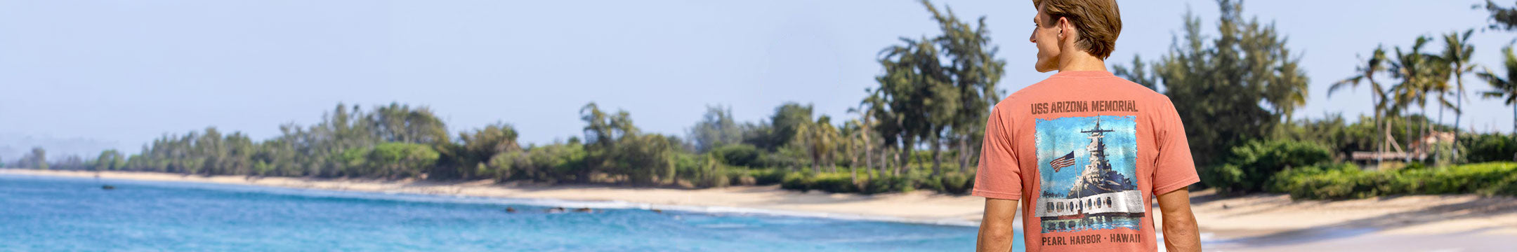 Person wearing a t-shirt with a graphic design standing on a beach.