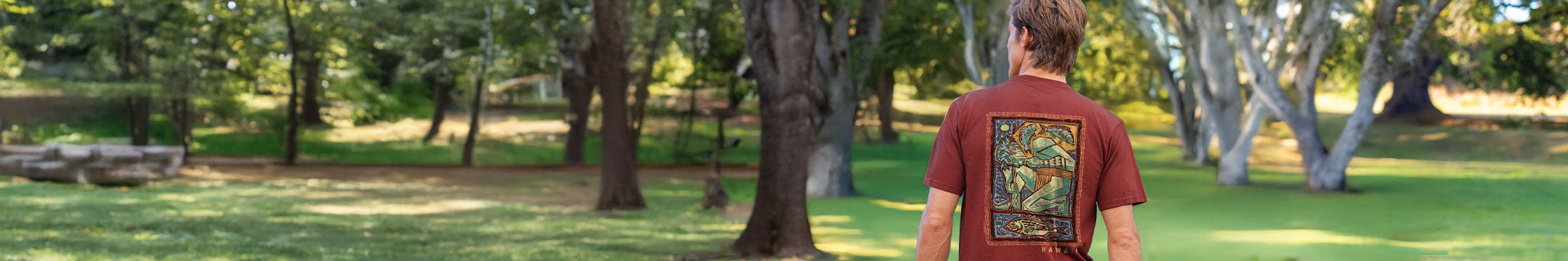 Person wearing a Whiskey shirt with a colorful design in a park