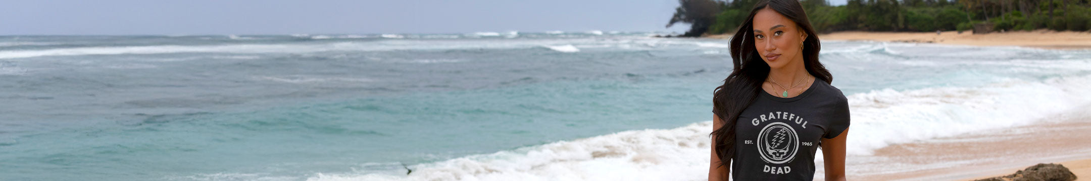 Woman in a black t-shirt standing on a beach with ocean and sky in the background