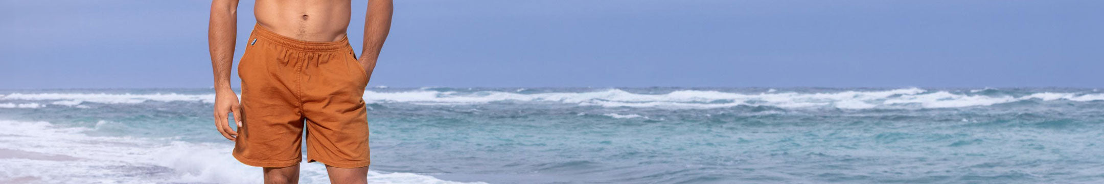 Person wearing yellow shorts standing on a beach with ocean waves in the background