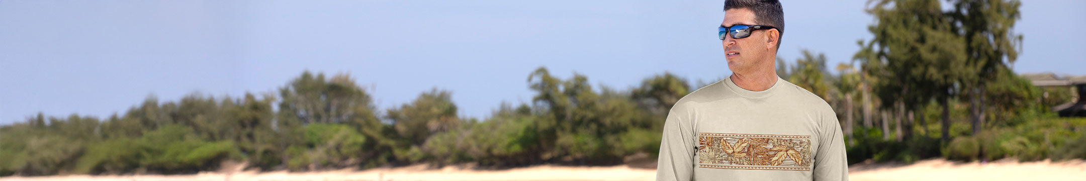 Man wearing sunglasses and a white shirt with text standing outdoors with trees in the background